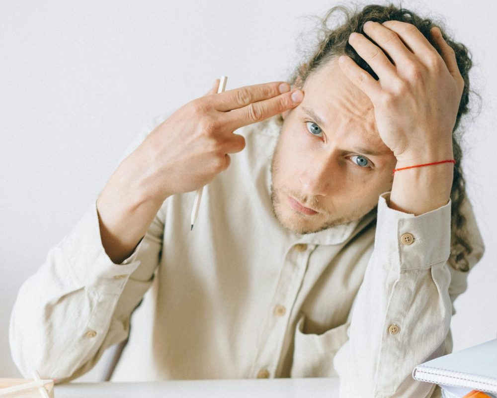 A young adult in an office feeling stressed and overwhelmed by workload.
